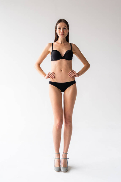 beautiful young woman in black lingerie posing on photo studio background - Foto, Bild