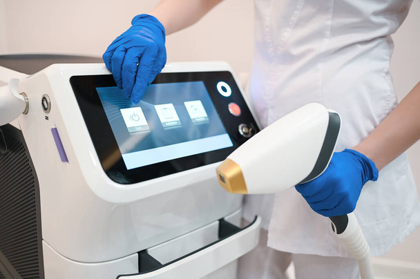 Апарат для лазерної епіляції та рук косметолога в медичних рукавичках. Концепція епіляції та спа
 - Фото, зображення