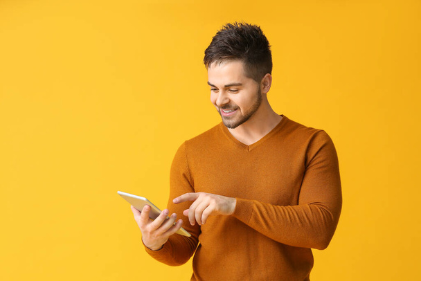 Giovane uomo con tablet computer su sfondo a colori - Foto, immagini