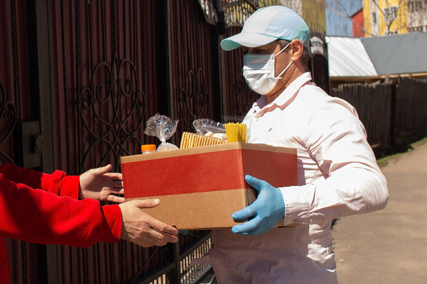 der Freiwillige übergibt den Bedürftigen eine Schachtel Lebensmittel - Foto, Bild
