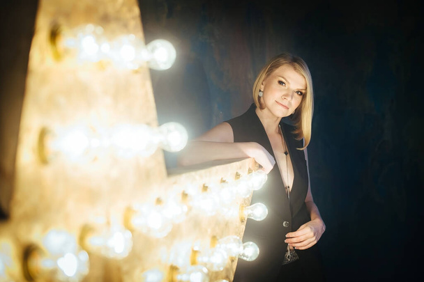 Beautiful blonde young woman on the background of a star with lamps. - Foto, afbeelding