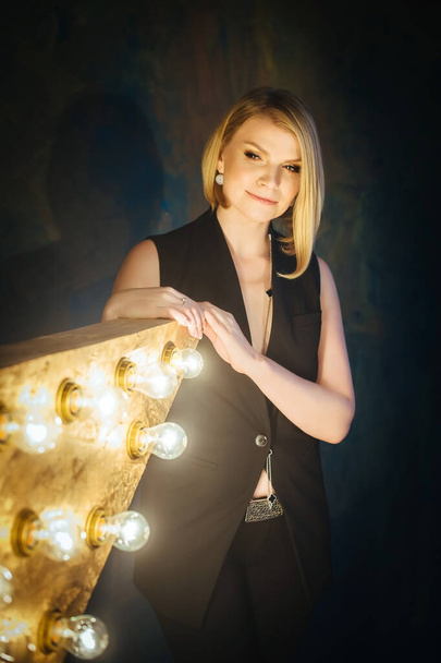 Portrait of beautiful blonde young woman on the background of a star with lamps. - Foto, afbeelding