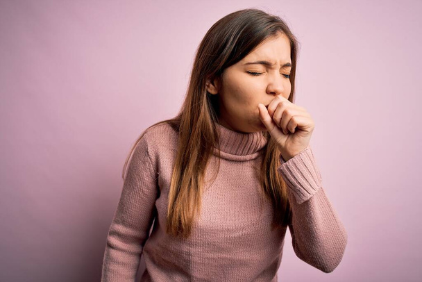 Beautiful young woman wearing turtleneck sweater over pink isolated background feeling unwell and coughing as symptom for cold or bronchitis. Health care concept. - Fotografie, Obrázek