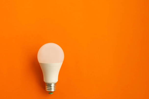 a lâmpada de poupança eléctrica sobre um fundo laranja
 - Foto, Imagem
