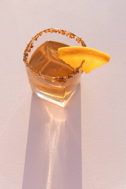 Κοκτέιλ, ποτό με πορτοκαλί απομονωμένο σε ανοιχτό ροζ φόντο και σκληρό φως, καλοκαιρινό πάρτι ηλιοβασιλέματος - Φωτογραφία, εικόνα