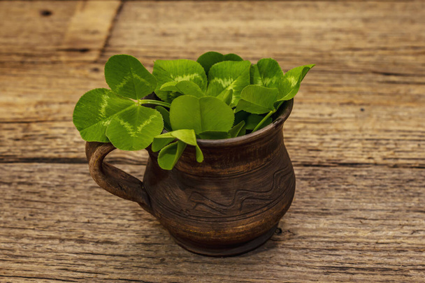 Fresh clover bouquet in ceramic cup. Good luck symbol, St.Patrick's Day concept. Old wooden boards background - Photo, Image