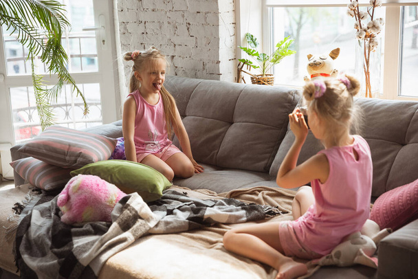 Quiet little girls playing in a bedroom in cute pajamas, home style and comfort, taking a photo, having fun - Valokuva, kuva