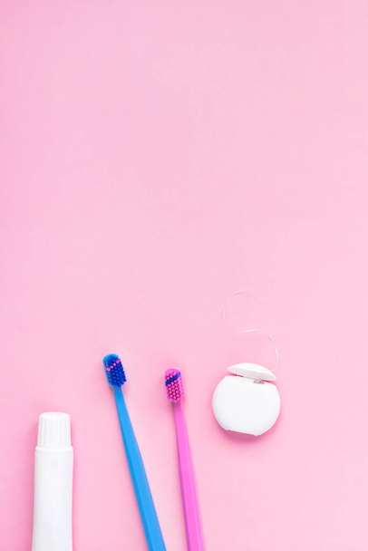 Teeth hygiene and oral dental care products on color pink and blue background with copy space. Blank tube of toothpaste and brushes. Flat lay, top view composition, mockup. Morning concept - Photo, image