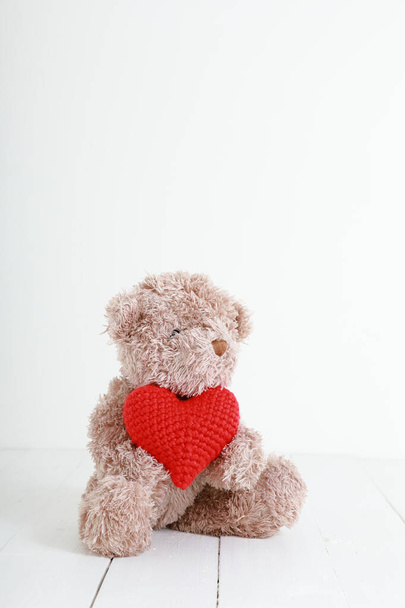 Αρκουδάκι με κόκκινη καρδιά σε λευκό ξύλο. Concept love, ημέρα του Αγίου Βαλεντίνου με χώρο αντιγραφής. - Φωτογραφία, εικόνα