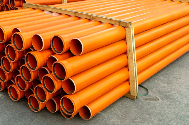 Orange plastic pipes for plumbing or water stacked on a pallet - Photo, Image