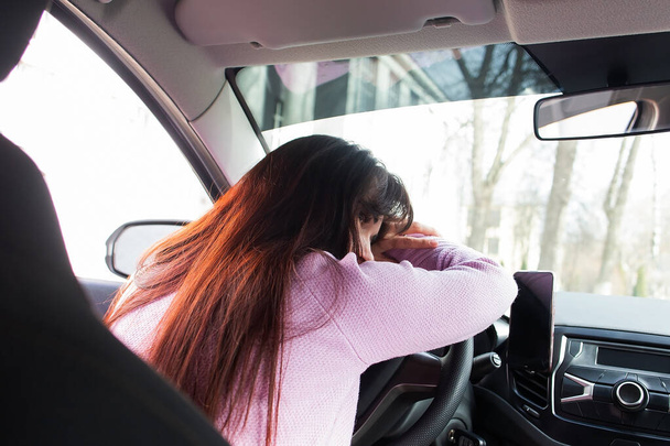 Το κουρασμένο κορίτσι πίσω από το τιμόνι ενός αυτοκινήτου - Φωτογραφία, εικόνα