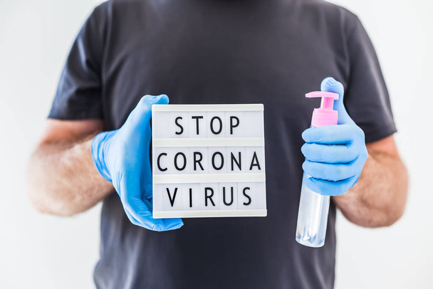 Käsi sanitizer hygienia alkoholi geeli pullot ja valolaatikko tekstiä Lopeta Coronavirus käsissä mies yllään lateksi lääketieteelliset käsineet ja suojaava naamio aikana coronavirus COVID-19 pandemioita. Terveydenhuolto
 - Valokuva, kuva
