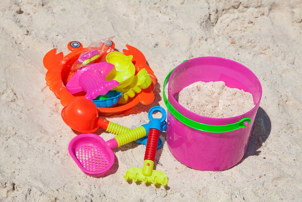 Bright plastic toys on a sandy beach - Fotoğraf, Görsel