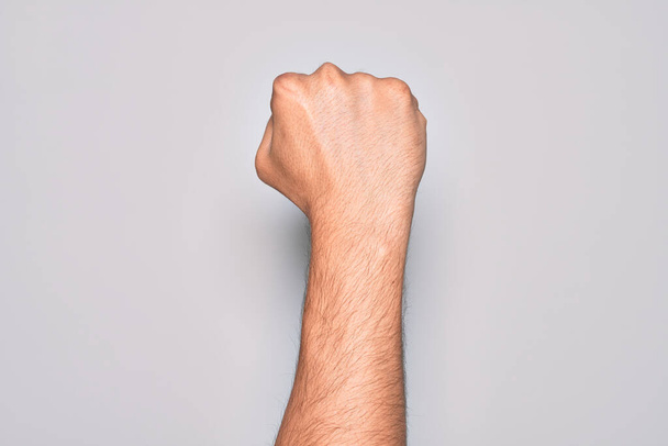 抗議と革命のジェスチャー、力と力を表現する拳を行う孤立した白い背景の上に指を示す白人の若者の手 - 写真・画像