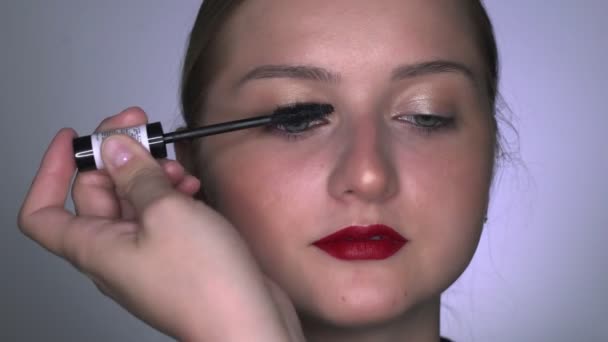Makijażysta robi profesjonalny makijaż dla młodej kobiety w studiu kosmetycznym. Make up Artist farby rzęsy rzęsy tusz - Materiał filmowy, wideo