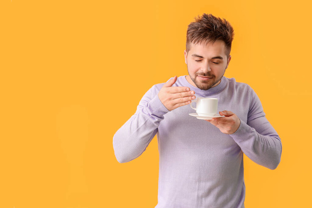 Young man with cup of hot coffee on color background - Photo, image