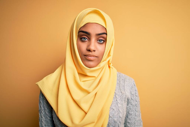 若いです美しいですアフリカ系アメリカ人の女の子身に着けていますイスラム教徒ヒジャーブ上の隔離された黄色の背景見て眠いと疲れ,疲労とハングオーバーのために疲れ,午前中に怠惰な目. - 写真・画像