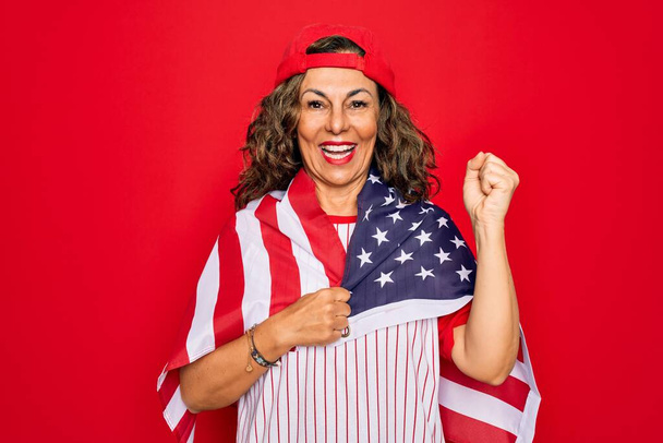 Orta yaşlı vatansever kadın beyzbol ekipmanı giyiyor. Elinde Amerikan bayrağı var. Gururla bağırıyor, zaferi kutluyor ve başarıyı kutluyor. - Fotoğraf, Görsel