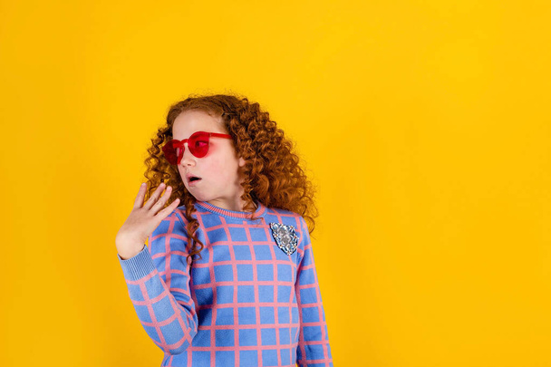red haired , emotional girl with red glasses on a yellow background - Photo, Image