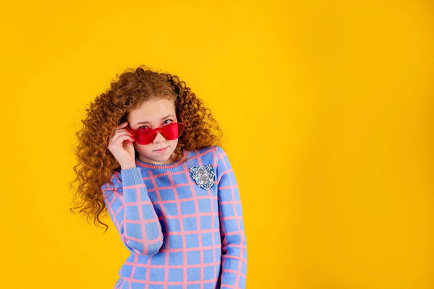 red haired , emotional girl with red glasses on a yellow background - Photo, image