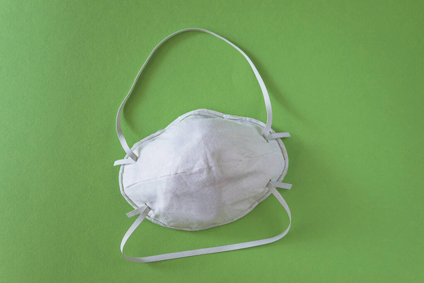 Λευκή μάσκα προστασίας του αναπνευστικού σε πράσινο φόντο - Φωτογραφία, εικόνα