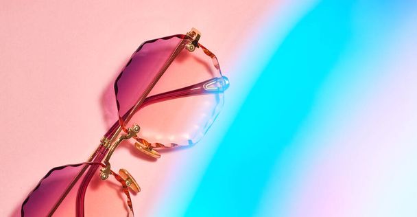 Round, female, with colored lenses and grained edges, sunglasses on pink background. - Photo, Image