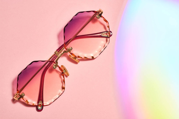 Kulaté, samičí, s barevnými čočkami a zrnitými okraji, sluneční brýle na růžovém pozadí. - Fotografie, Obrázek