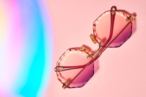 Round, female, with colored lenses and grained edges, sunglasses on pink background. - Foto, Imagem