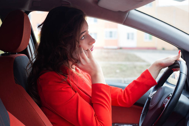 A Business lady in red suit behind the wheel of a car - Foto, imagen