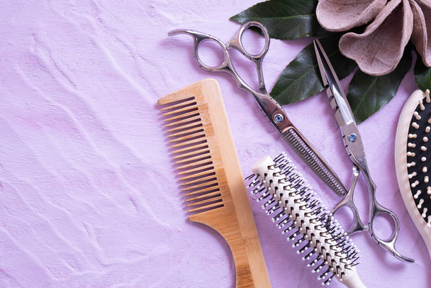 Деревянная расческа для волос, ножницы и деревянные украшения лежат на текстурном фоне и все на розовом фоне
 - Фото, изображение