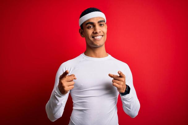 Young handsome african american sportsman wearing sportswear over red background pointing fingers to camera with happy and funny face. Good energy and vibes. - Fotó, kép