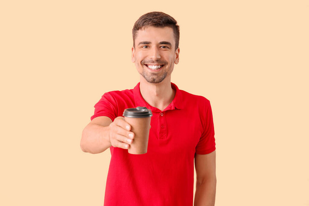 Young man with cup of hot coffee on color background - Fotó, kép