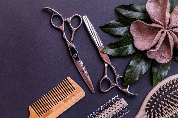 a pair of scissors for a hairdresser, combs and decoration made of wood lie on a textural background and everything on a blue background - 写真・画像