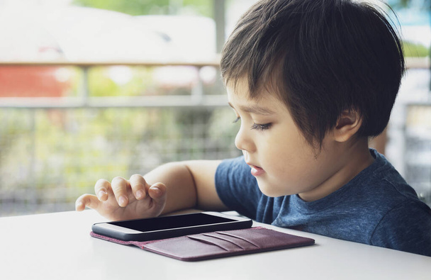 Селективное внимание малыша, играющего в игру на смартфоне, мальчика, использующего мобильный телефон, дошкольного ребенка, стирающего мультфильмы на мобильном телефоне в ожидании коррекции родителей, концепции "Дети с технологиями"
 - Фото, изображение