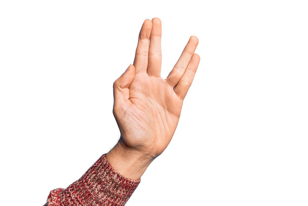 Mano de hombre joven caucásico mostrando los dedos sobre el saludo aislado fondo blanco haciendo saludo vulcano, mostrando la palma de la mano y los dedos, cultura freak - Foto, imagen