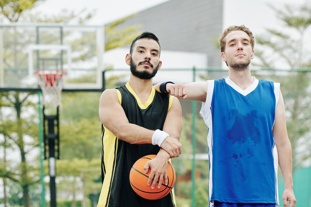 Tired sweaty basketball players standing on outdoor court after playing game - Photo, Image
