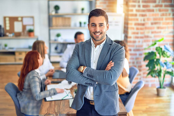 Group of business workers working together. Young handsome businessman standing smiling happy looking at the camera at the office - Фото, изображение
