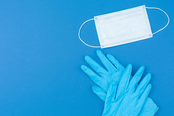 Medical gloves and mask on blue background.  - Zdjęcie, obraz