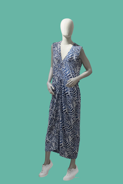Ganzkörperlange weibliche Schaufensterpuppe trägt ein blaues Kleid mit Blumenmuster, isoliert auf grünem Hintergrund. Keine Markennamen oder Copyrightobjekte.  - Foto, Bild
