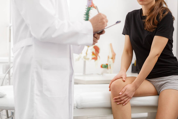 Male doctor examining female patient suffering from knee pain. Medical exam. Chiropractic, osteopathy, post traumatic rehabilitation, sport physical therapy. Alternative medicine, pain relief concept - Foto, immagini