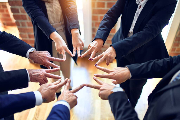 Üzletemberekből álló csoport, akik egy körön állnak és szimbólumot csinálnak ujjaikkal az irodában.. - Fotó, kép