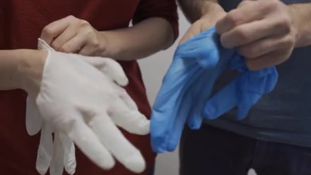 Twee mensen doen rubber latex handschoenen aan op hun handen. - Video