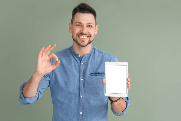 Jóképű férfi táblagéppel mutatja OK gesztus a színes háttér - Fotó, kép