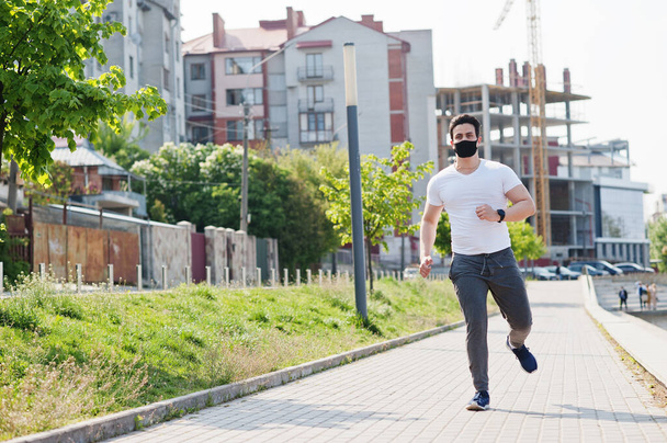 Porträt Sport arabischer Mann mit schwarzer medizinischer Gesichtsmaske läuft während der Coronavirus-Quarantäne im Freien. - Foto, Bild
