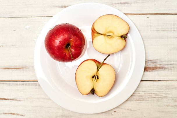 Ripe red apples on a plate on a wooden background. - Photo, Image