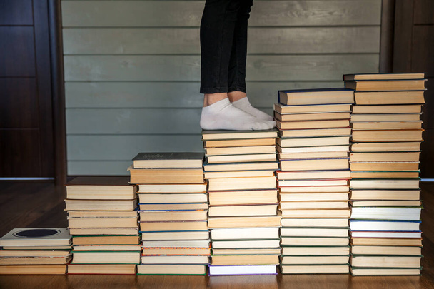 Nő lábak fehér zokni megy fel a könyvek lépcsőjén - Fotó, kép