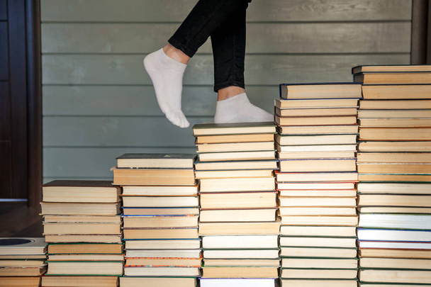 Γυναίκα πόδια σε άσπρες κάλτσες ανεβαίνει τις σκάλες βιβλίων - Φωτογραφία, εικόνα