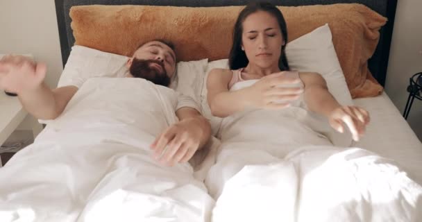 Shocked young couple oversleep and looking at each other with big eyes while sitting on bed . Man and woman covering blanket lying on the pillows and waking up with screaming. - Séquence, vidéo