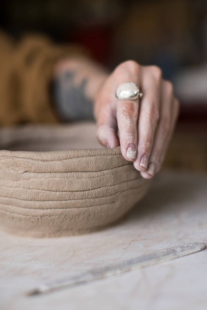 Crop hand of female artisan in ring making clay pot from coils while working in workshop - Valokuva, kuva