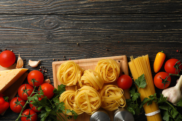 Composition with pasta and ingredients for cooking on wooden background, top view - Foto, afbeelding